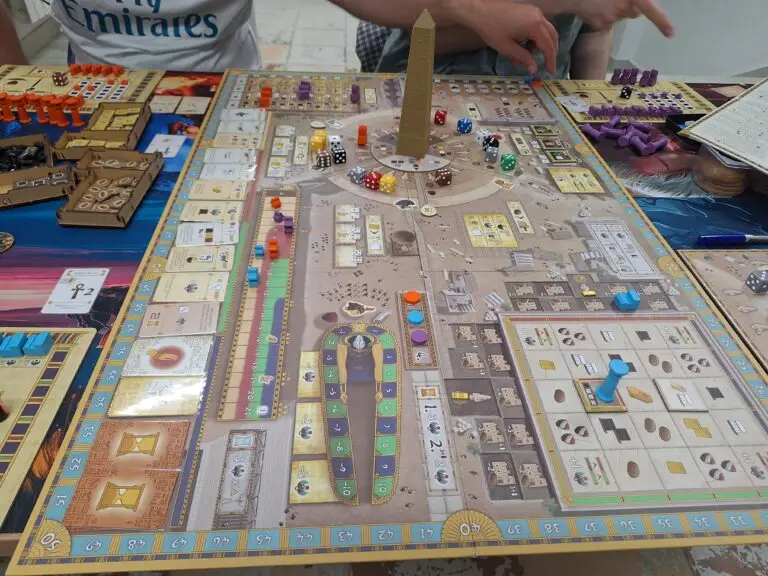 Club members playing Tekhenu: Obelisk of the Sun at Warsaw Board Game Club — game board with obelisk piece, dice, and resource tokens