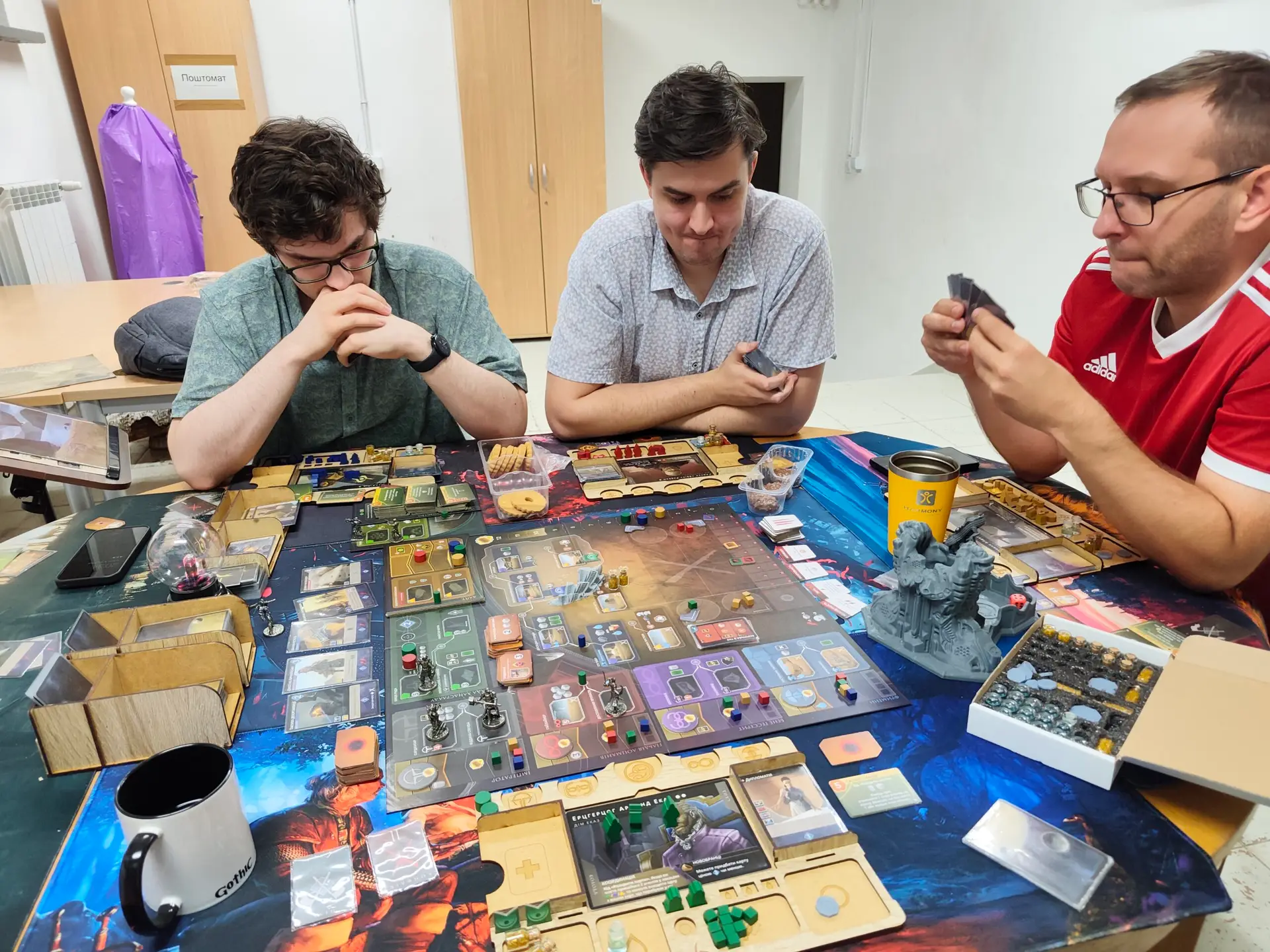 Троє гравців, заглиблених у партію в Dune: Imperium під час зустрічі клубу настільних ігор у Варшаві